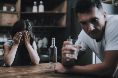 Kız ağlıyor mutfak ile sarhoş baba oturur. Adam Modern Mutfak tutun bardak alkol döner ve utanç ile uzak görünüyor sandalyeye oturur. Kızı kapakları yüzünü elleri olan. Alkolizm kavramı