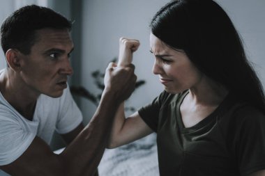 Mücadele ve kadın ve erkek arasında evde kavga. Evli çift portresi gri yatağın üstüne oturan ve savunarak. Öfkeli koca yatak odasında hanımları el çatışma tutun. Aile içi şiddet kavramı