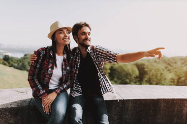 Genç çift oturma çıkıntı ve Parkı'nda arıyorum. Genç adam ve kadın ile birlikte Beton kenarında oturan sırt çantaları. Doğanın güzel manzarayı çift. Seyahat kavramı