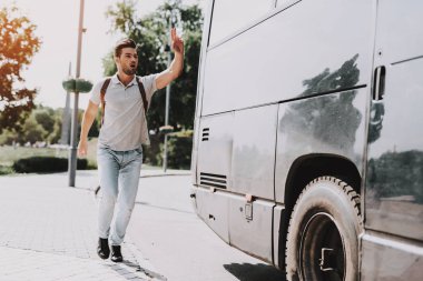 Genç yakışıklı turist neredeyse geç için otobüs. Sırt çantası çalıştırdıktan sonra tur otobüsü ve el sallayarak tarafından durdurmak için otobüs şoförü soran adam. Seyahat, turizm ve insanlar kavramı. Aktif yaşam tarzı