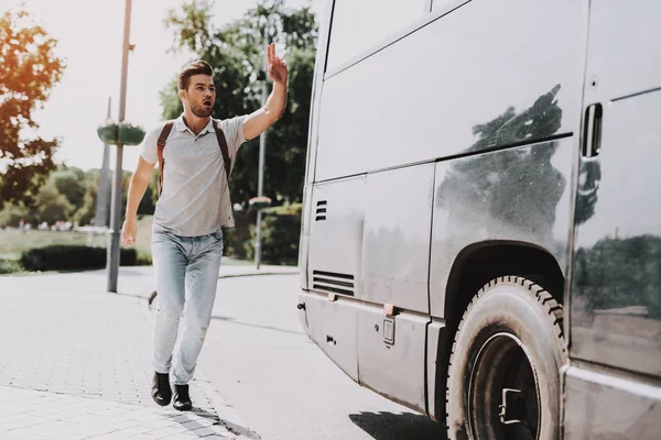 Genç yakışıklı turist neredeyse geç için otobüs. Sırt çantası çalıştırdıktan sonra tur otobüsü ve el sallayarak tarafından durdurmak için otobüs şoförü soran adam. Seyahat, turizm ve insanlar kavramı. Aktif yaşam tarzı
