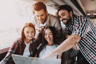 Kağıt harita tutan genç gülümseyen insanlar grubudur. Mutlu seyahat planlama rota birlikte arıyorsunuz tarafından haritaya casualy giyinmiş. Seyahat, turizm ve dostluk kavramı. Yaz tatili