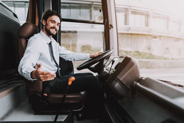 Smiling Man Driving Tour Bus. Professional Driver. Young Happy Man wearing White Shirt and Black Tie Sitting on Driver Seat. Attractive Confident Man at Work. Traveling and Tourism Concept