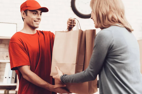 Courier Delivery. Flowers Deliveryman. Worker Man Arab Nationality. White Interior. Deliveryman Arab Nationality. Courier in Orange Clothes. Express Delivery. Gives Paper Package. Paper Package.