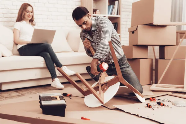 Assemble Furniture. Man Repairing Chair. Man Collects Chair. Furniture Assembler Doing New Furniture. Woman on Sofa with Laptop. Bright Interior. Craftsman with Tools Repairs Chair. Furniture Repair.