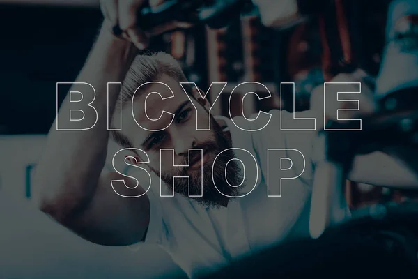 Bicycle Shop. Salesman Looking the Bicycle. Young Beard Man. Hipster Man Thinking. Man Searching the Problem of Bicycle. Different Bicycles on Background of Man. Man Sales the Bicycles.