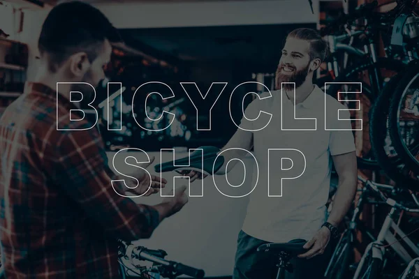 Bicycle Shop. Salesman Showing Bicycle Saddle to Customer. Customer Choosing the Saddle on His Bike. Hipster Male Salesman. People Happy and Smiling. Man Sales the Bicycles Equipment.