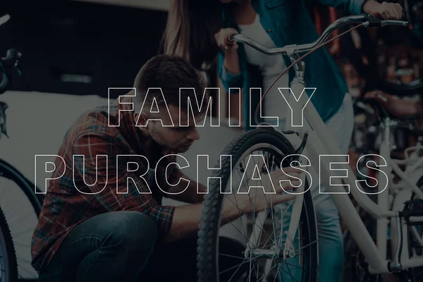 Family Purchases. Customers Choosing a Bicycle. Customers is Couple of Man and Woman. Man Holding a Catalog of Bikes. Couple Using a Bicycle. People Looking on Bike. Man Checks the Wheel of Bike.