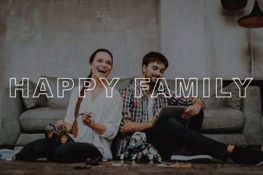Oturma odası. Genç bir çift. Otur. Kat. Toplamak. Robotlar. Adam. Tablet. Birlikte çalışır. Yardım. Kız. Gülümseyerek. Güzel. Mutlu. Serbest zaman. İyi eğlenceler. Aile. Robot tasarımı. Ev. Mutluluk.