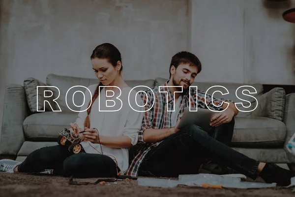 Young Couple. Sit. Floor. Living Room. Collect. Robots. Guy. Tablet. Work Together. Help. Girl. Smiling. Beautiful. Happy. Leisure Time. Have Fun. Family. Designing Robots. Home. Happiness.