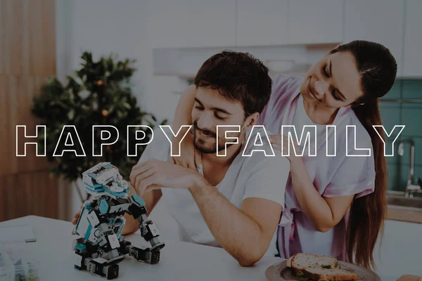 Man. Collect. Robot. Kitchen. Girl. Hugs. Smiling. Beautiful. Pink Robe. Happy Together. Leisure Time. Have Fun. Family. Designing Robots. Home. Spare-Time. Off-Time. Happiness. Bubbly Relationships.