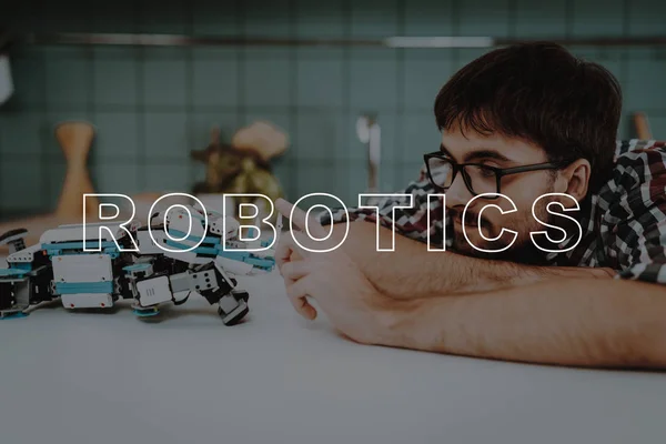 Guy. Posing. Busy. Focused. Robot. Kitchen. Leisure Time. Designing Robots. Happy. Young. Relationships. Help. Man. Smiling. Beautiful. Have Fun. Family. Home. Happiness. Light. Glasses.