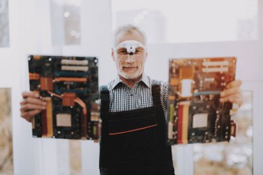 Tamirci bilgisayar hizmet iki anakartlar Holding var. Kırık Laptop bileşenidir. Adam bilgisayar büyüteç gözlük. Ana tahta tamiri. Erkekte iş giysisi bilgisayar bakım merkezi.