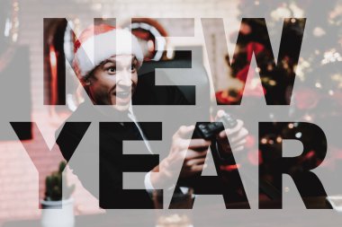 Ofis Yöneticisi çalış Gamepad New Year's Eve üzerinde. Şakası. Şenlikli ruh hali. Noel ağacı fon. Hafta sonu dinlenme iş başında. Santa Claus şapka. Heyecanlı işadamı gülümseyerek. Video oyunu.