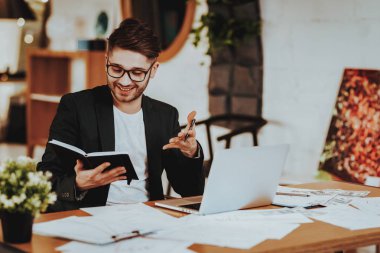 İş adamı iş üstünde not etmek seyir Laptop. Taşınabilir bilgisayarda uzaktan çalışma işyerinde mutlu başarılı genç metin yazarı Yöneticisi takım elbise ve gözlük gülümseyen portresi oturur.