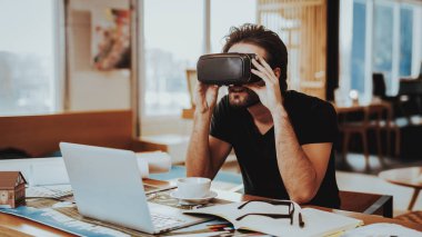 Mutlu Tasarımcısı uzaktan çalışma ve test Vr. portresi neşeli beyaz adam takıyor sanal gerçeklik gözlükler oturup Danışma Laptop istimal ang becerikli alet tutan el kadar kapalı.