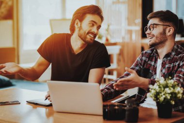 Çocuklar kullanım dizüstü Coworking kapalı iken gülümseyerek. İki mutlu serbest çalışma alanı ve fikirleri tartışmak masada rahat kıyafetler Sit giymek. Takım çalışması ve işbirliği kavramı