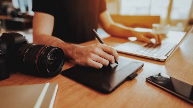 Portre erkek grafik tasarımcı el çalışma. Tablo Retoch fotoğraf dijital Tablet Stylus kalem, Laptop klavye ve kamera ile kapalı kullanma oturan adam. Freelancing ve mesafe iş kavramı