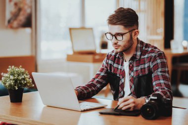 Dizüstü bilgisayarda çalışan ciddi Freelancer portresi. Yakışıklı Hipster grafik tasarımcı tablo rötuş fotoğraf dijital Tablet kapalı Stylus kalem ile kullanarak, gözlük oturur giyer. Mesafe iş kavramı