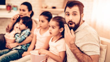 Neşeli bir aile evde korkunç film izlerken. Patlamış mısır yemek ve gülen evde kanepede otururken çocuklar. Küçük şirin çocuklar oyuncaklarla, veliler vardır kanepe, Hugging, çizgi film izlerken