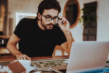 Masa başında oturan adam portresi Projesi'nde çalışıyor. Genç grafik tasarımcı Illustrator Laptop ekranında odaklı masada oturan gözlüklü sakallı. Yaratıcı iş kavramı