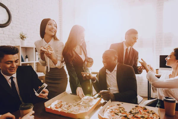 Team of Managers Have Lunch in Modern Office. Rest after Business Meeting. Modern Office Concept. Cooperation with Colleagues. Businessman with Team. Pizza in Box. Businessman in Suit.