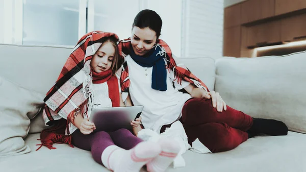 Sick Family Sitting on Sofa in Checkered Blankets. Mother and Daughter. White Sofa in Room. Unhappy Girl. Disease Concept. Healthcare and Healthy Lifestyle Concept. Using Serviettes. Girl with Laptop.
