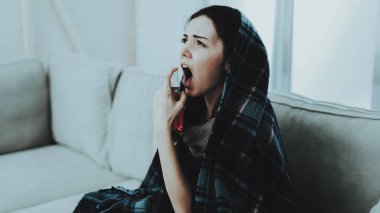 Kadın soğuk fularlı evde kanepede ile. Hasta genç kadın. Oda beyaz kanepe. Mutsuz bir kadın. Hastalık kavramı. Sağlık ve sağlıklı yaşam konsepti. Mutsuz kız. Modern tıp.