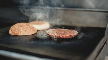 Yakın çekim. Yemek hamburger gıda kamyon işçisi. Sokak gıda kavramı. Şehirde yiyecek. Abur cubur satış. Sandviç hazırlanması. Sağlıksız yiyecek. Ellerinde eldiven. Lezzetli sıcak Hamburder.