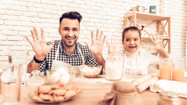 Evde yemek. Mutlu bir aile. Babalar günü. Kız ve erkek yemek. Un yüzünde olan adam. Birlikte vakit geçirmek. Yemek masada. Hamur pişirin. Yüzler ve un elinde. Kız uğraşıyormuş. Bisküvi plaka üzerinde.