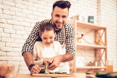 Evde yemek. Mutlu bir aile. Babalar günü. Kız ve erkek aşçı gıda. Adam ve çocuk masasında. Birlikte vakit geçirmek. Peynir rendeleyin. Rende elinde. Domates ve salatalık. Baba ve kızı birlikte.