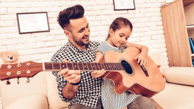 Adam ve kız gitar çalıyorum. Gitar çalıyorum. Piyano birlikte oynar. Piyano ve gitar. Baba ve kızı kanepe. Birlikte vakit geçirmek. Babalar günü. Adam oyun kız ile. Beyaz iç. Adam kanepede kızla.