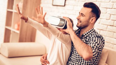 Joystick elinde. Sanal gerçeklik maskesi. Baba ve kızı. Birlikte vakit geçirmek. Babalar günü. Douhter ile oynayan adam. Video oyunu. Beyaz iç. Koltukta oturuyor. Kız maske sanal gerçeklik.