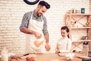 Evde yemek. Baba beslemeleri kız. Cam suyu dökün. Mutlu bir aile. Babalar günü. Kız ve erkek aşçı gıda. Adam ve çocuk masasında. Birlikte vakit geçirmek. Baba elinde sürahi ile. Aile evde.