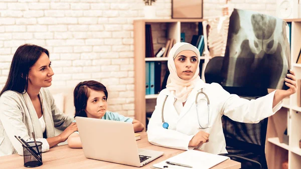 Arabic Doctor Appointment Holding X-Ray Film. Pediatrician Appointment Mom with Sick Son. Confident Muslim Female Doctor Wearing Hijab. Hospital Concept. Healthy Concept. Child Patient Visiting Doctor