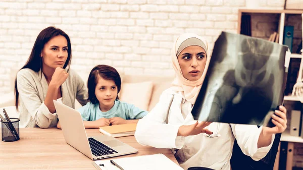 Arabic Doctor Appointment Holding X-Ray Film. Pediatrician Appointment Mom with Sick Son. Confident Muslim Female Doctor Wearing Hijab. Hospital Concept. Healthy Concept. Child Patient Visiting Doctor