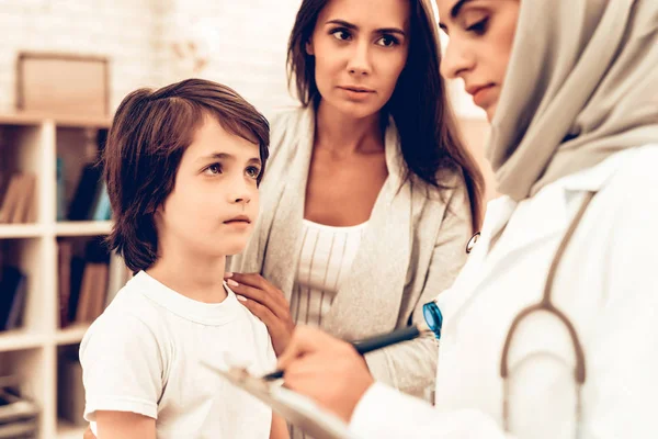 母亲与儿子在阿拉伯医生的任命 自信的穆斯林女医生 儿科医生的孩子 医院理念 健康的理念 儿科医生写处方 儿童患者 — 图库照片