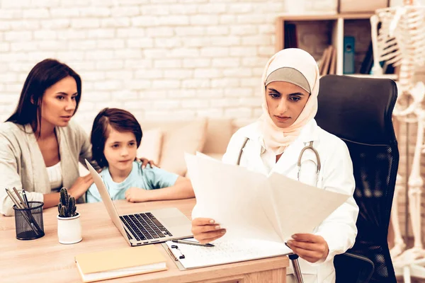 Arabic Doctor Reading Medical Examinations Results. Confident Muslim Female Doctor. Child at the Pediatrician. Hospital Concept. Healthy Concept. Child Patient Visiting Doctor.