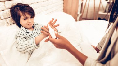 Tıp hasta oğlu için yalan yatak veren anne. Hasta çocuk hapları vermeye bakım anne. Tahriş olmuş çocuk istiyorum ilaç yok. Hasta çocuğa bardak su veren endişeli anne. Hastane kavramı. Sağlıklı kavramı. 