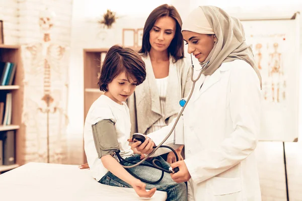 Arabic Female Doctor Checking Blood Pressure Boy. Child at the Pediatrician. Hospital Concept. Healthy Concept. Child Patient Visiting Doctor. Doctor Checking Blood Pressure. ill Boy Lying on Bed