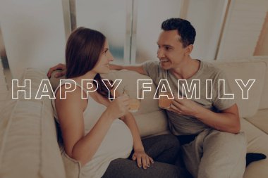 Cam bardak portakal suyu. Hamile kadın kanepe üzerinde yatıyor. Mutlu genç aile. Hamile kız mide ellerinde. Kadın mide. Göbek kız beklenti gebelik. Evde hamile Sit. Gülümsüyor anne.