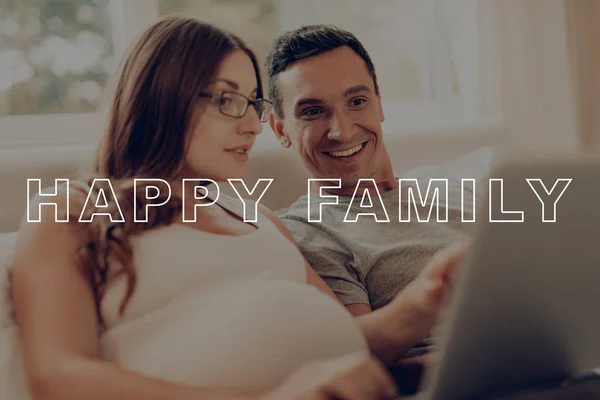 Pregnant Girl Work on Laptop. Guys Lying on Bed. Rest Together. Happy Young Family. Preggers Sit at Home. Man use Smartphone. Belly Girl Anticipation Pregnancy. Pregnant Woman Smiling Happily.