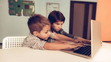 Masada oturan ve evde dizüstü kullanarak iki erkek. Genç erkek. Gri Laptop. Dijital aygıt kullanarak. Klavyeyi kullanarak. Modern eğlence kavramı. Genç gömlek. Ahşap masa üstünde Laptop. Küçük çocuk.