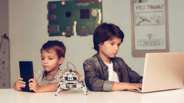 Masada oturan ve Robot Programlama iki erkek. Genç çocuk gömlek. Kapalı sevinç. Modern hobi kavramı. Modern teknoloji. Robot mühendislik kavramı. Genç Robor ile. Eğlenmek için yenilik.