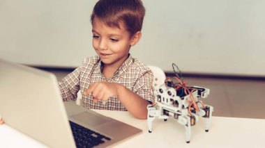 Küçük çocuk gömlek programlama robot evde. Genç çocuk gömlek. Dizüstü bilgisayar kullanarak. Modern hobi kavramı. Modern teknoloji. Robot mühendislik kavramı. Eğlenmek için yenilik. Genç Robor ile.