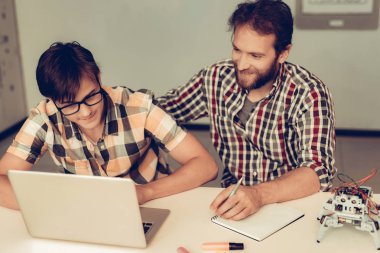 Sakallı baba yardım oğul için Program Robot evde. Genç çocuk gömlek. Dizüstü bilgisayar kullanarak. Modern hobi kavramı. Modern teknoloji. Robot mühendislik kavramı. Genç adam yenilik için eğlenceli sakallı.