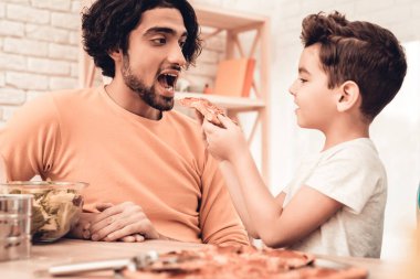 Mutfakta pizza yemek mutlu Arap aile. Müslüman aile. Boy gülümseyerek. Genç Arap kadın. Modern mutfak evde. Mutfak eşyaları kullanan adam. Genç aile. Ahşap masa mutfak. Masasına yemek.