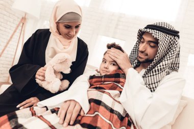 Battaniye Divan aile ile hasta Arap çocuk. Anne-baba ile çocuk kapalı. Mutsuz çocuk. Genç Arap kadın. Müslüman aile. Sağlık kavramı. Damalı battaniye. Grip olan çocuk. Beyaz kanepe.