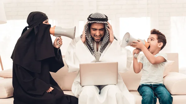 妻子和儿子与扬声器尖叫父亲 黑面纱里的女人父母与儿童室内 心烦意乱的家庭拿着笔记本电脑的人 年轻的阿拉伯女人 穆斯林家庭 在家中使用数字设备 — 图库照片