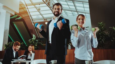 Kurumsal spor yaşam tarzı. Sağlık iş adamları. Ofis çalışanları dumbell ile çalışma. İşçiler Fitness egzersizleri yapıyor. Yoga pratik. Gülümseyen için sağlıklı kadın çalışan adam.